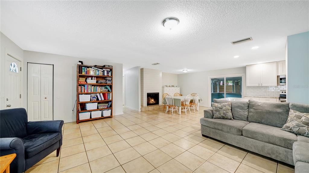 A living room with tile floors, a fireplace, a bookshelf, and an adjacent dining area — 745 WILDWOOD DRIVE, ST AUGUSTINE, FL