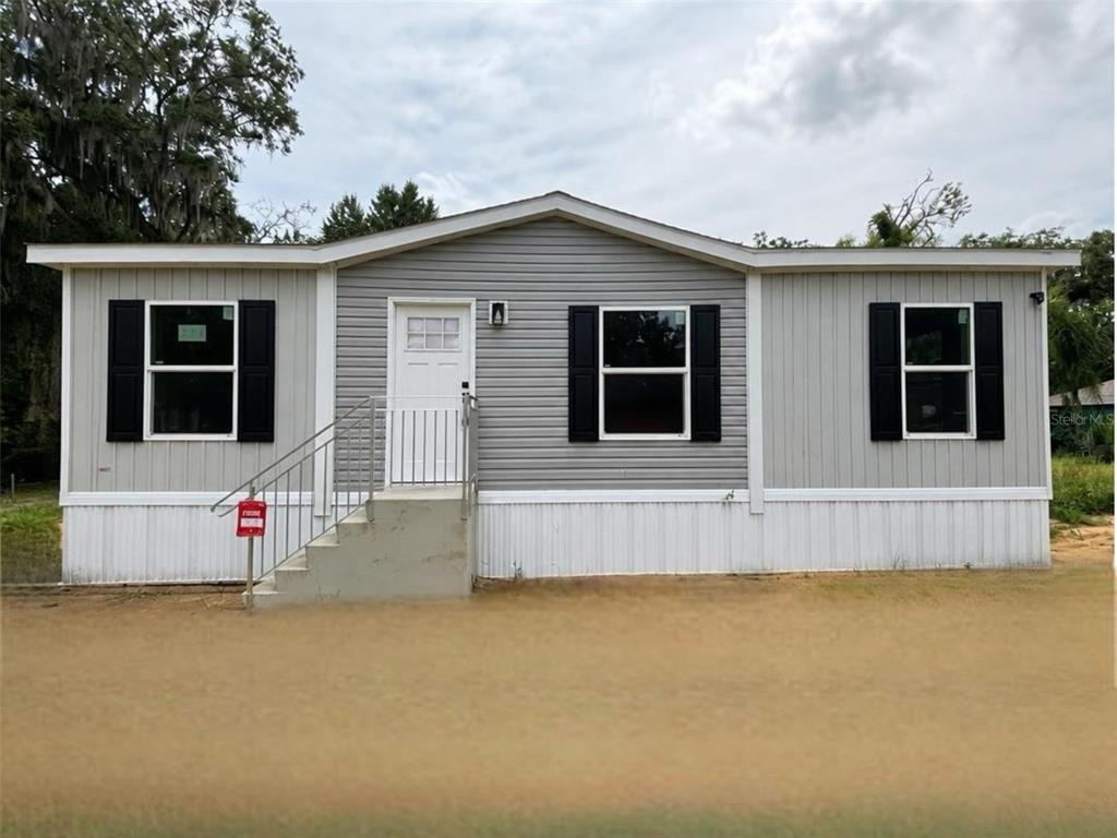A single-story manufactured home with grey siding, black shutters, and a concrete front staircase — 175 SMITH STREET, MULBERRY, FL
