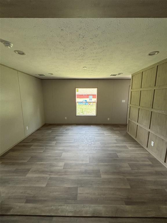 An empty room features wood-look plank flooring, recessed lighting, and a paneled accent wall — 175 SMITH STREET, MULBERRY, FL