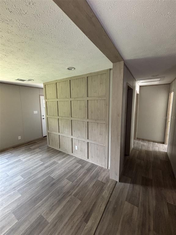 An interior view shows a living area with wood-paneled accent wall and light wood flooring — 175 SMITH STREET, MULBERRY, FL