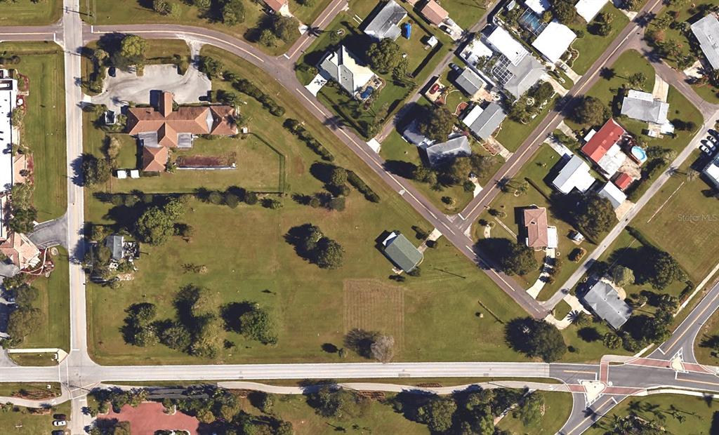 This aerial view shows a large, grassy lot with a few buildings and surrounding streets — 512 SHREVE STREET, PUNTA GORDA, FL