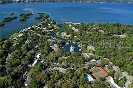 Aerial view of a waterfront residential community featuring a marina, tennis courts, and dense trees — 1628 CLOWER CREEK DRIVE UNIT 125, SARASOTA, FL
