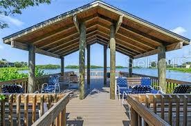 A wooden gazebo with a metal roof sits on a deck overlooking a calm body — 1628 CLOWER CREEK DRIVE UNIT 125, SARASOTA, FL