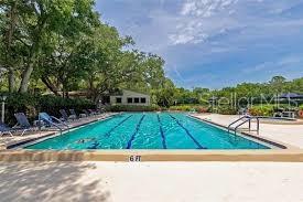 An outdoor rectangular swimming pool with lane markers and lounge chairs on a concrete deck — 1628 CLOWER CREEK DRIVE UNIT 125, SARASOTA, FL
