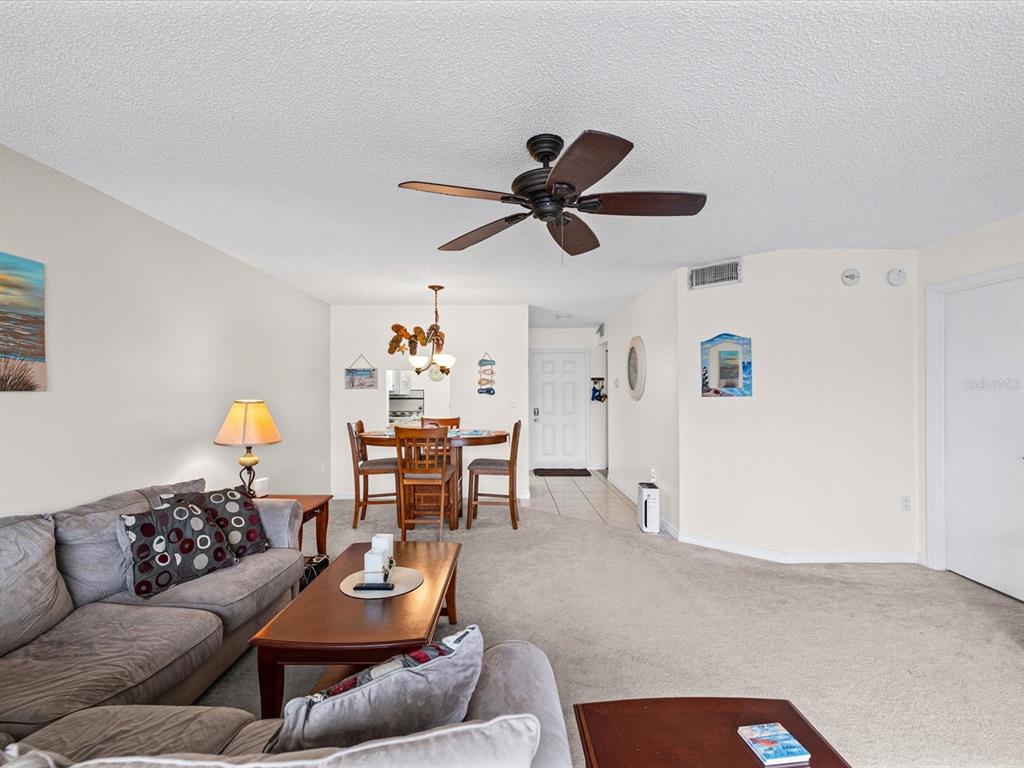 A living room and dining area with carpeted floors, a ceiling fan, and neutral walls — 6800 20TH AVENUE N UNIT 503, ST PETERSBURG, FL