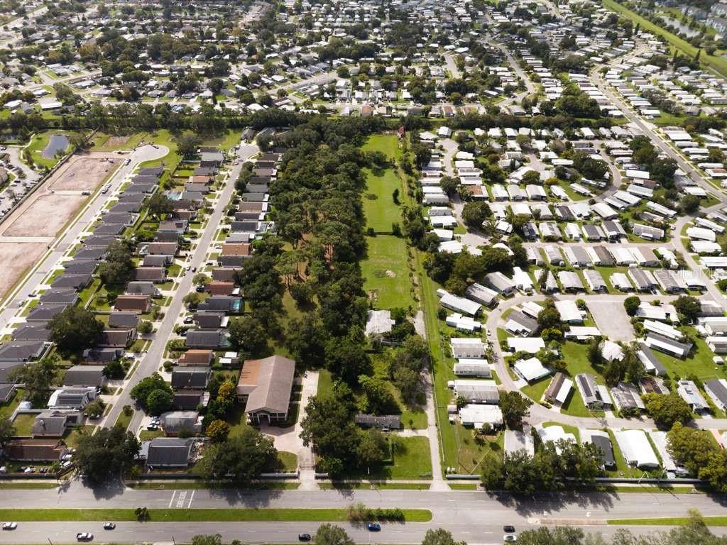 An aerial view shows a wooded lot situated between two residential neighborhoods and a road — 6250 PERSHING AVENUE, ORLANDO, FL