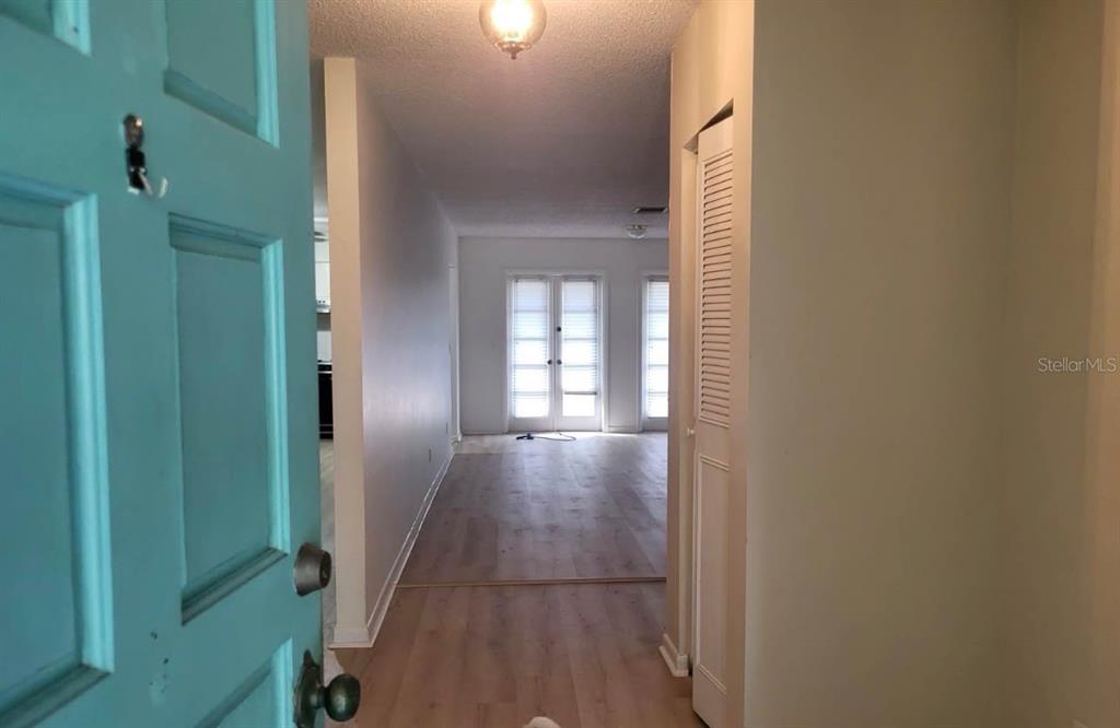 An entryway leads into a living area with light wood-look flooring and glass patio doors — 4716 W SAN RAFAEL STREET, TAMPA, FL