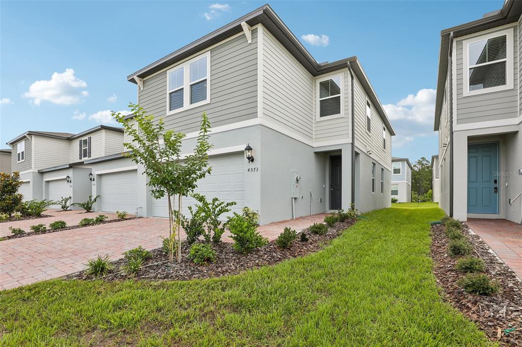 A two-story townhouse with a gray stucco and siding exterior, a garage, and a lawn — 4573 RANGELAND WAY, ST CLOUD, FL