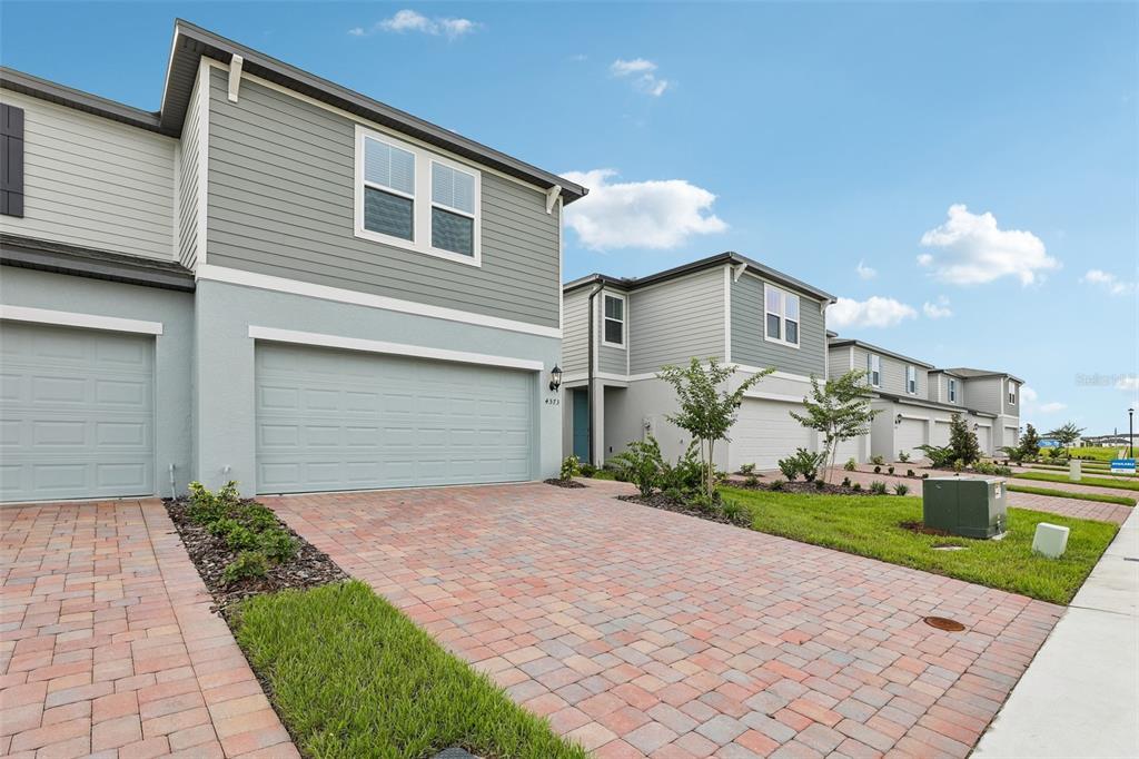 A row of modern two-story townhomes with light gray siding and paved driveways — 4573 RANGELAND WAY, ST CLOUD, FL