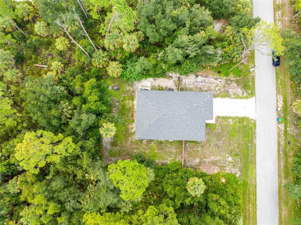 An aerial view shows a house with a gray roof surrounded by dense green trees — 18346 SAGAMORE AVENUE, PORT CHARLOTTE, FL