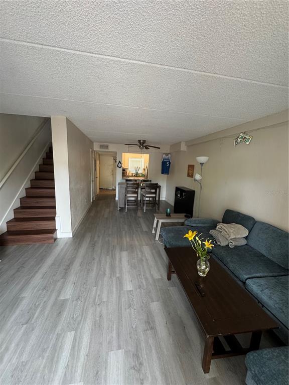 A living room with wood-look flooring, a staircase, and an open kitchen in the background — 2864 SOMERSET PARK DRIVE UNIT 2864, TAMPA, FL