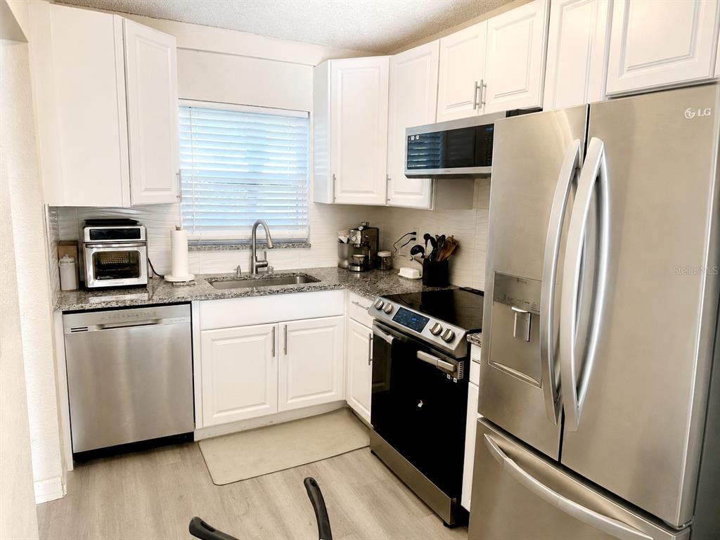 A kitchen features white cabinets, stainless steel appliances, and granite countertops — 2864 SOMERSET PARK DRIVE UNIT 2864, TAMPA, FL