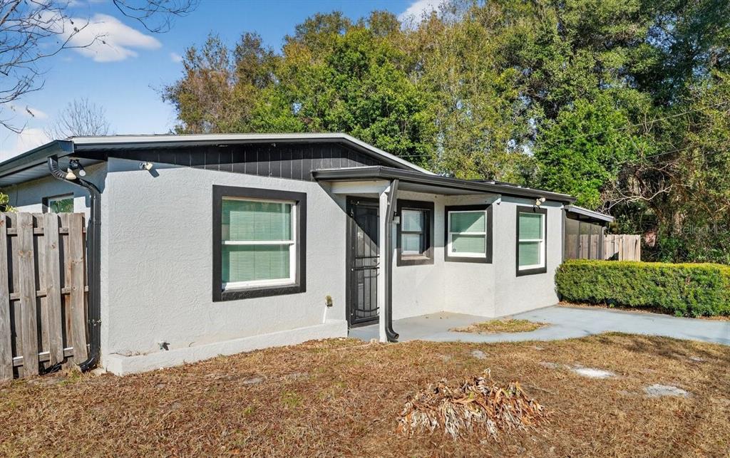 A single-story house with gray stucco walls, black trim, and a small front porch — 493 W BALTIMORE DRIVE, DELAND, FL