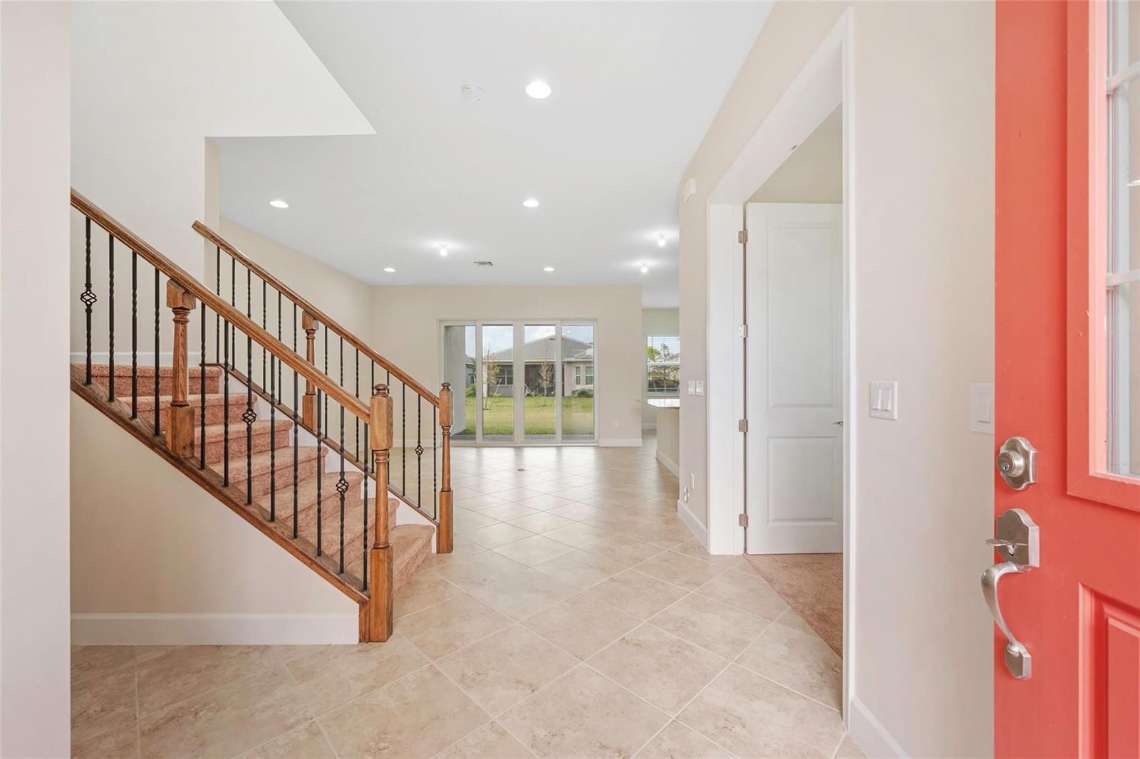 An entryway features a staircase with wood railings, tile flooring, and a red front door — 5573 Zestar Lane, Westlake FL 33470, WESTLAKE, FL