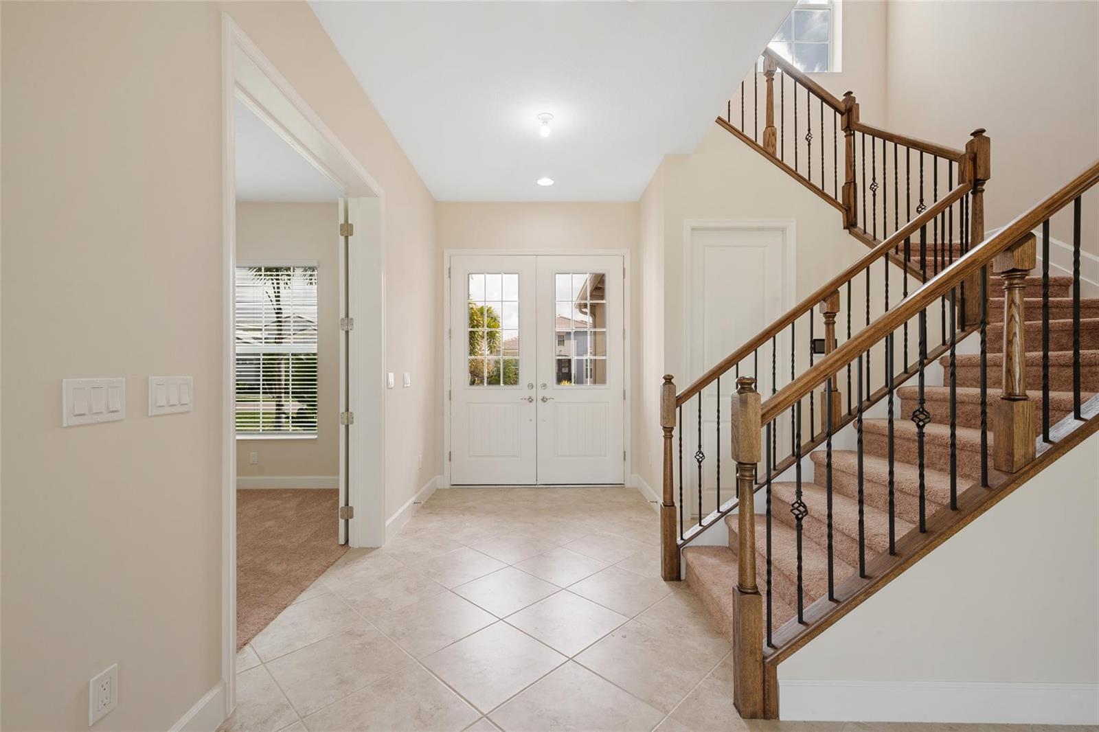 A foyer features tile flooring, a carpeted staircase with wood railings, and double entry doors — 5573 Zestar Lane, Westlake FL 33470, WESTLAKE, FL