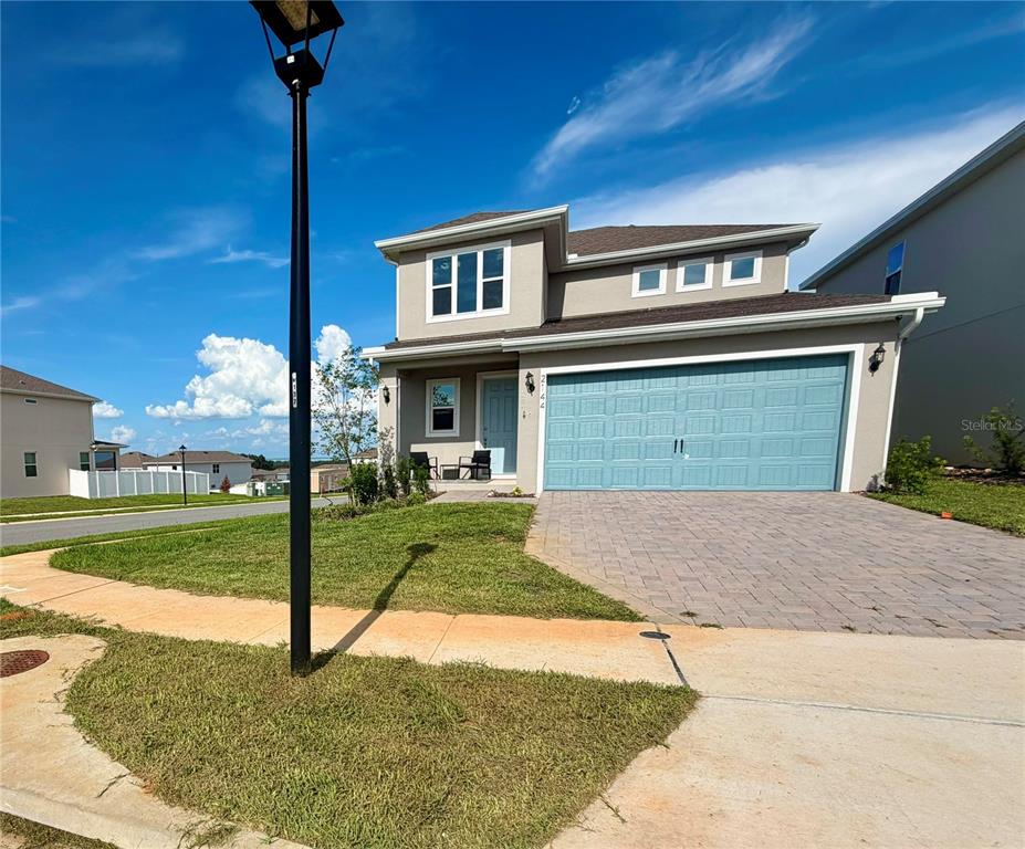A two-story suburban house with a light blue garage door and a paved driveway — 2144 KEYSTONE PASS BOULEVARD, MINNEOLA, FL