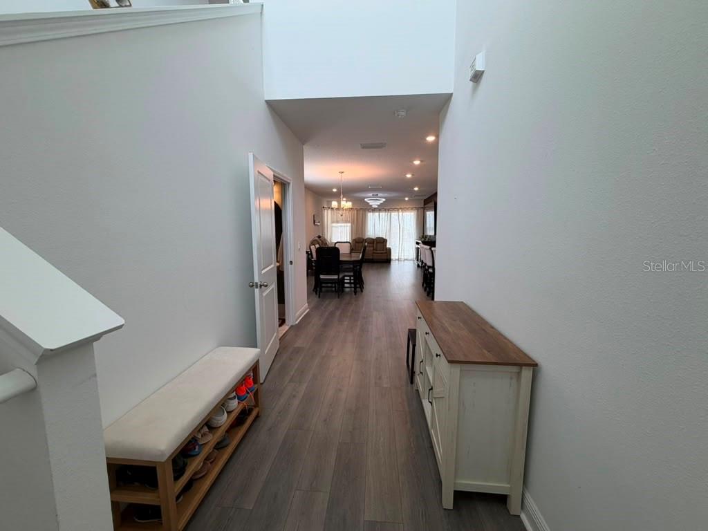 A hallway with wood-look flooring leads to an open-concept dining and living area — 2144 KEYSTONE PASS BOULEVARD, MINNEOLA, FL