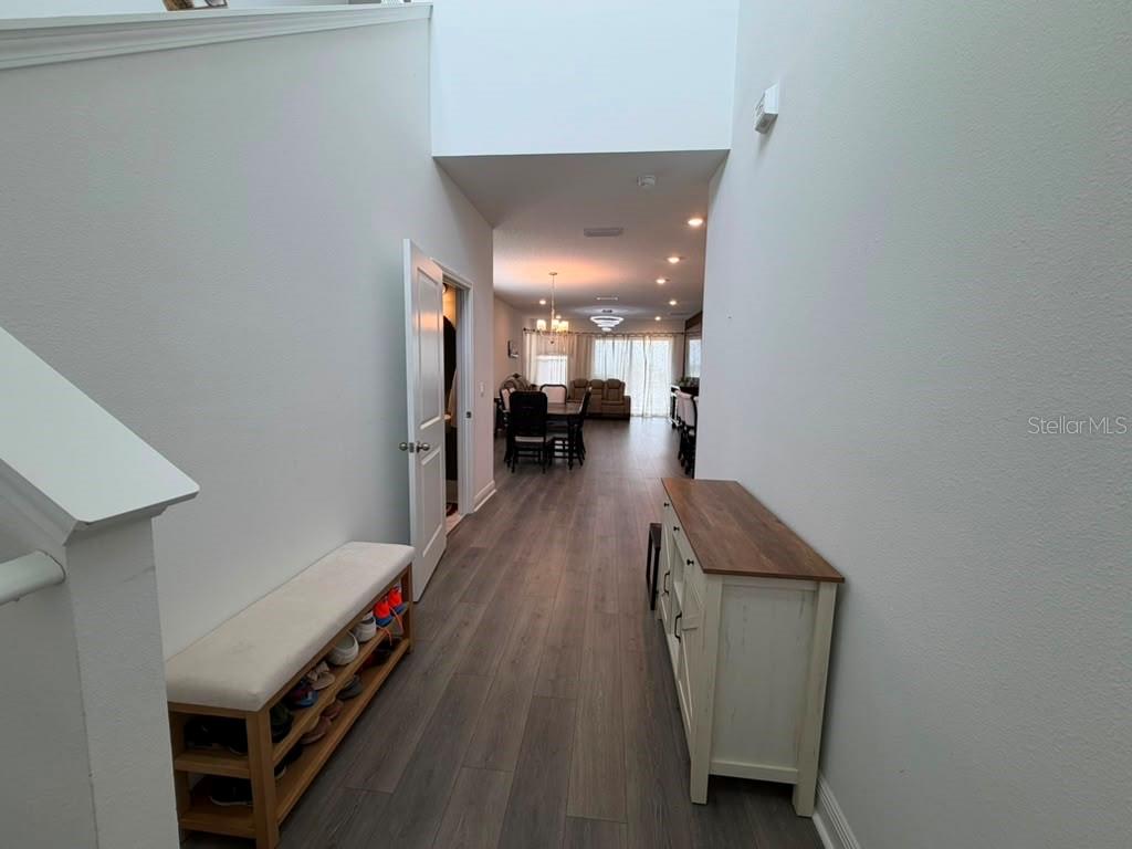 A hallway with wood-look flooring leads from a staircase toward a dining and living area — 2144 KEYSTONE PASS BOULEVARD, MINNEOLA, FL