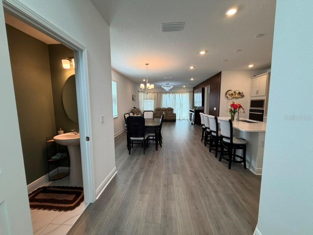 An open-concept living area features wood-look flooring, a dining set, and a kitchen island — 2144 KEYSTONE PASS BOULEVARD, MINNEOLA, FL
