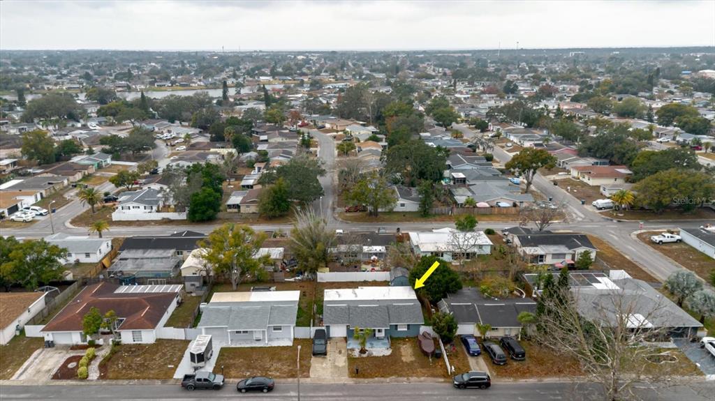 An aerial view shows a single-story house with a gray roof and a yellow arrow — 9731 RAINBOW LANE, PORT RICHEY, FL