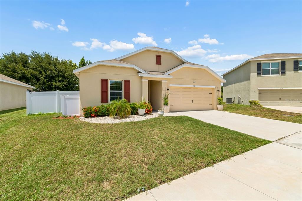 A single-story house with a beige stucco exterior, a two-car garage, and a front lawn — 11910 LITTLE VIOLET CIRCLE, RIVERVIEW, FL