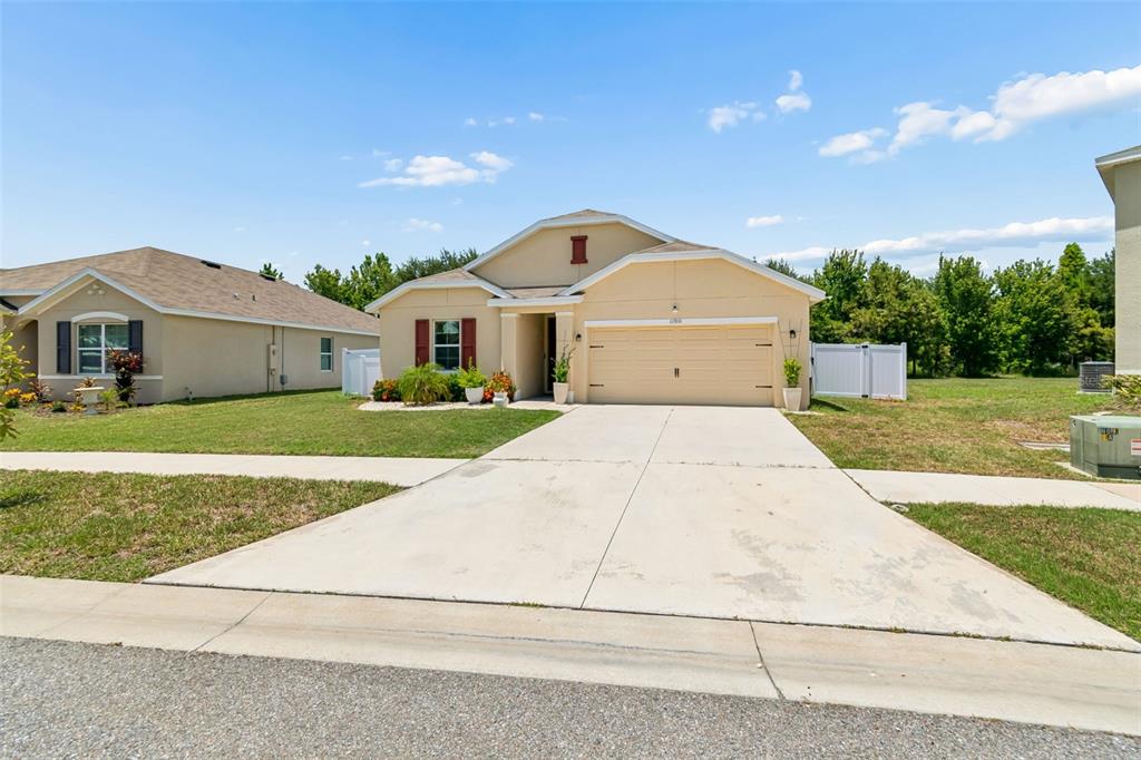 A single-story house with a beige stucco exterior, a two-car garage, and a concrete driveway — 11910 LITTLE VIOLET CIRCLE, RIVERVIEW, FL