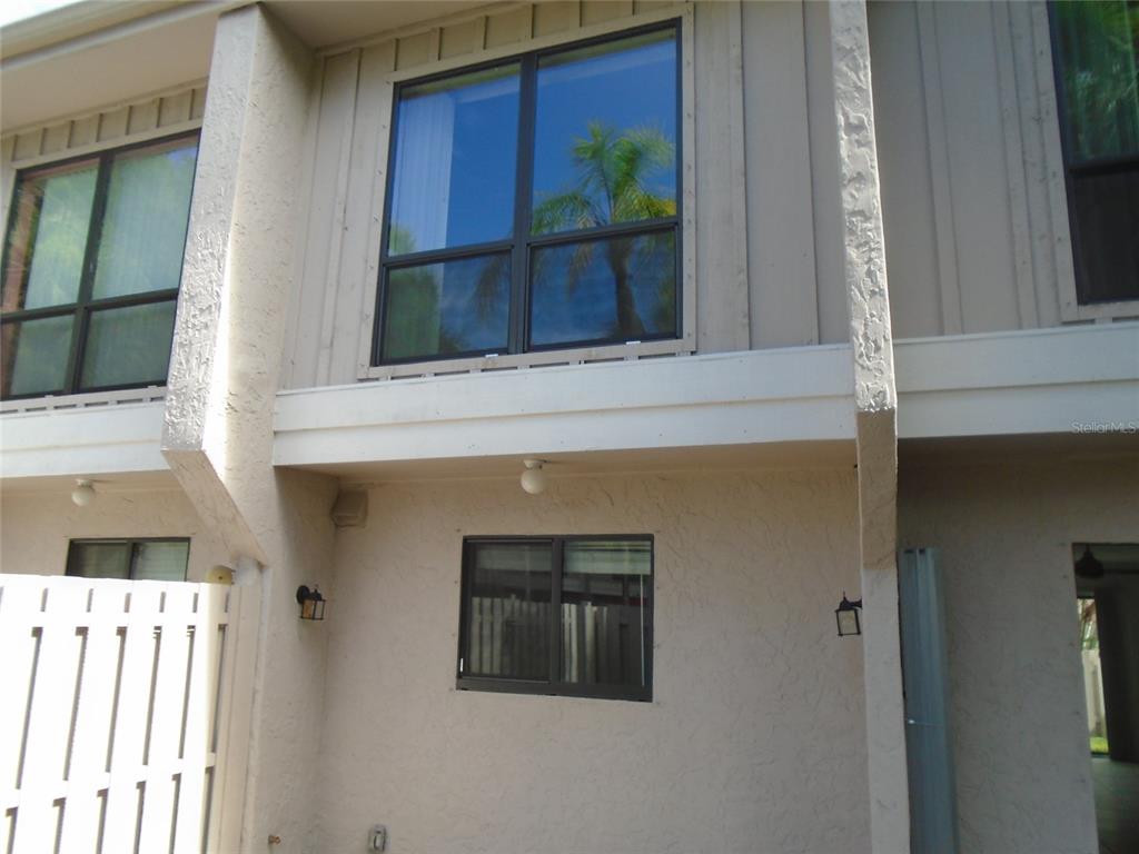 A two-story townhouse exterior features beige stucco walls, vertical siding, and dark-framed windows — 4001 BENEVA ROAD UNIT 349, SARASOTA, FL