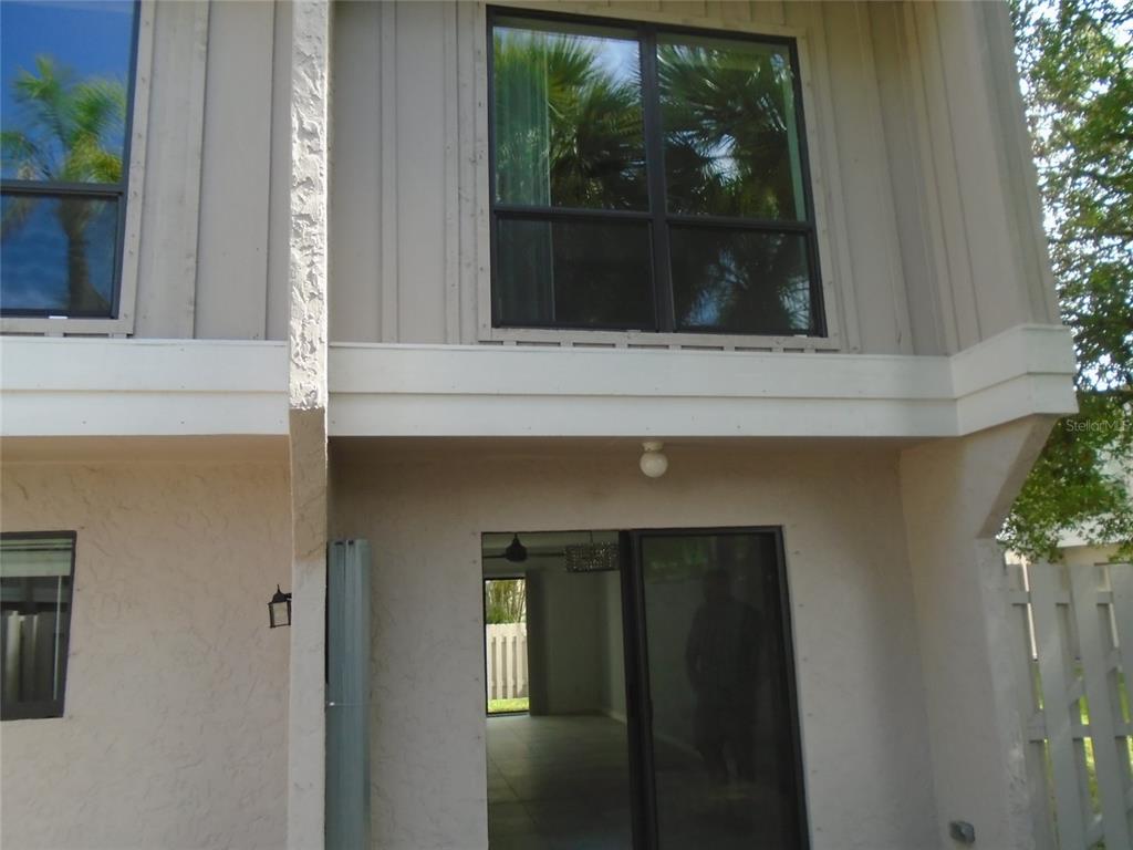 A two-story exterior view shows a sliding glass door, a window, and vertical siding — 4001 BENEVA ROAD UNIT 349, SARASOTA, FL