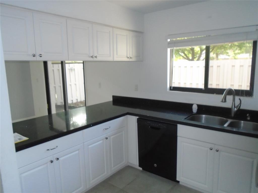 A kitchen features white cabinets, black countertops, a black dishwasher, and a window over the sink — 4001 BENEVA ROAD UNIT 349, SARASOTA, FL