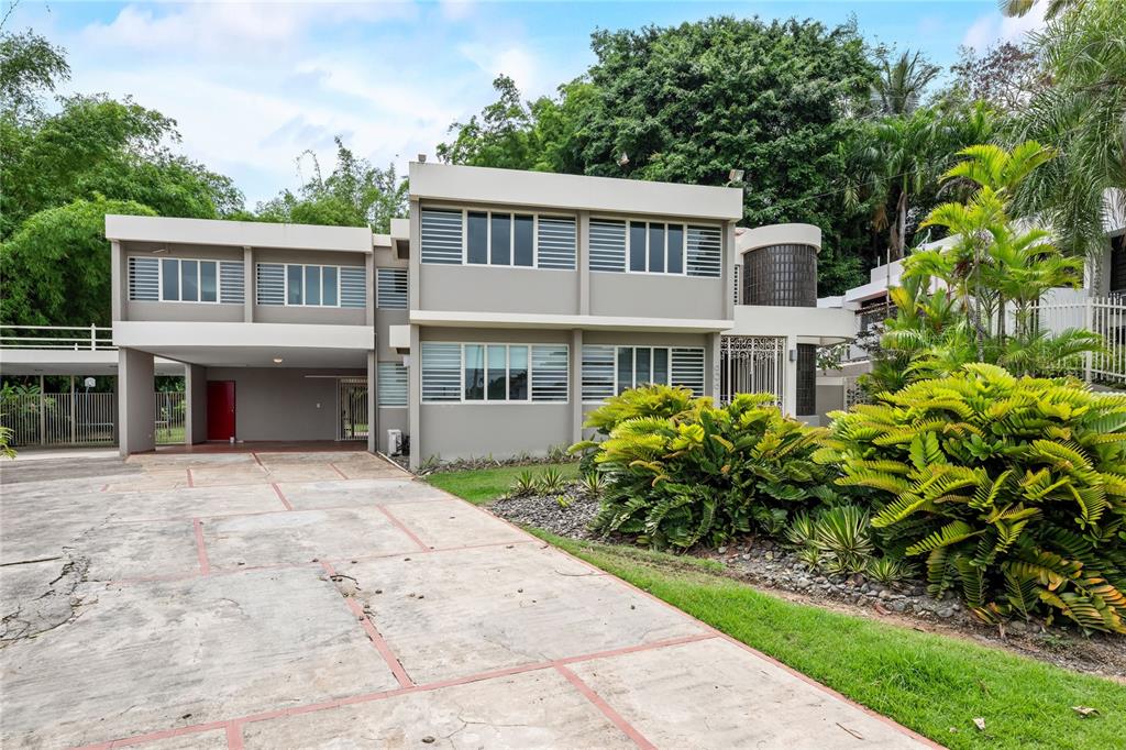 A two-story house with a concrete driveway, large windows, and lush landscaping in the front — Tintillo Hills 606 CALLE 1 TINTILLO HILLS, GUAYNABO, PR