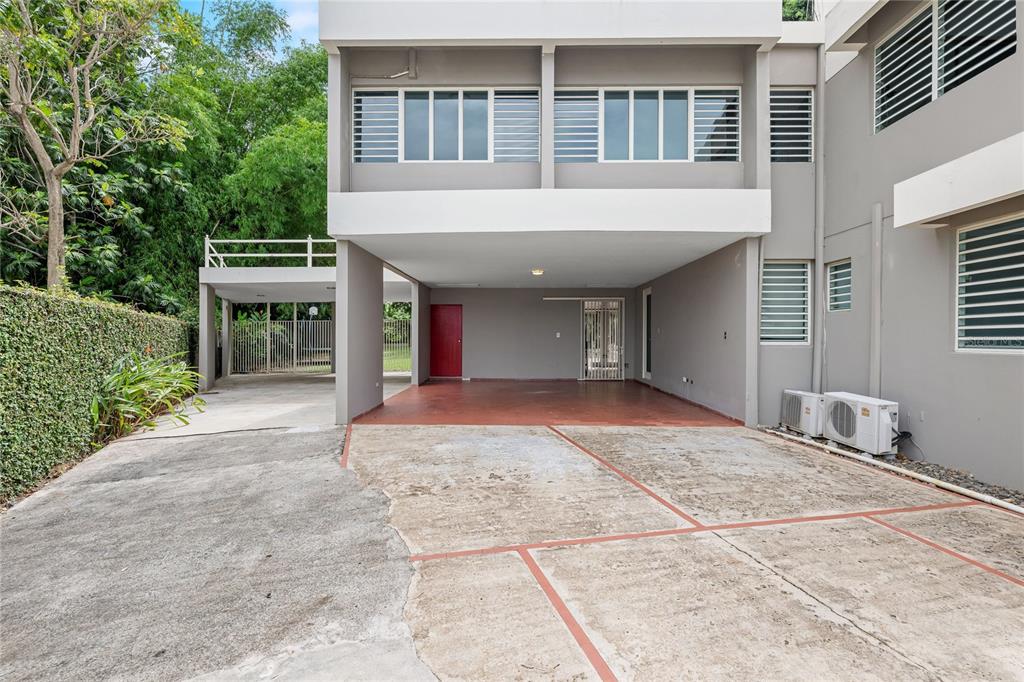 A concrete driveway leads to a covered parking area under a two-story gray building — Tintillo Hills 606 CALLE 1 TINTILLO HILLS, GUAYNABO, PR