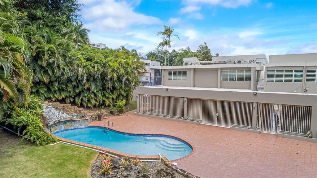 An outdoor swimming pool sits on a tiled patio next to a multi-story building — Tintillo Hills 606 CALLE 1 TINTILLO HILLS, GUAYNABO, PR