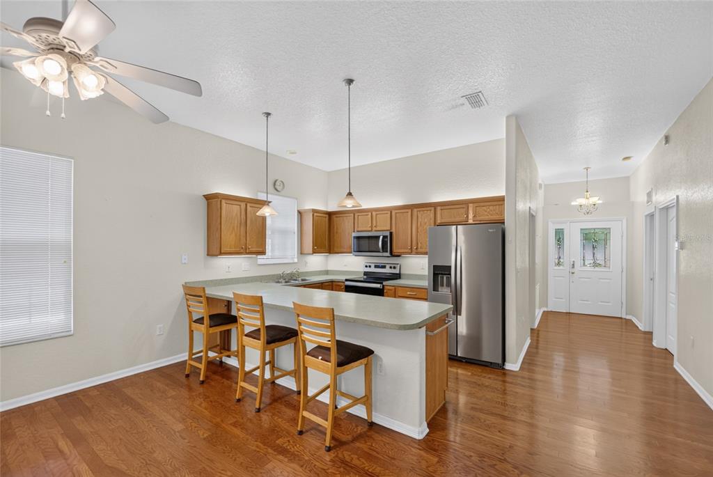 A kitchen with wood cabinets, stainless steel appliances, and a breakfast bar with three stools — 2216 NE 40TH TERRACE, OCALA, FL