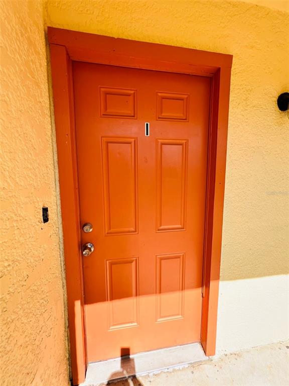 A bright orange exterior door with four panels and a single digit number — 2192 KNOX MCRAE DRIVE UNIT 1, TITUSVILLE, FL