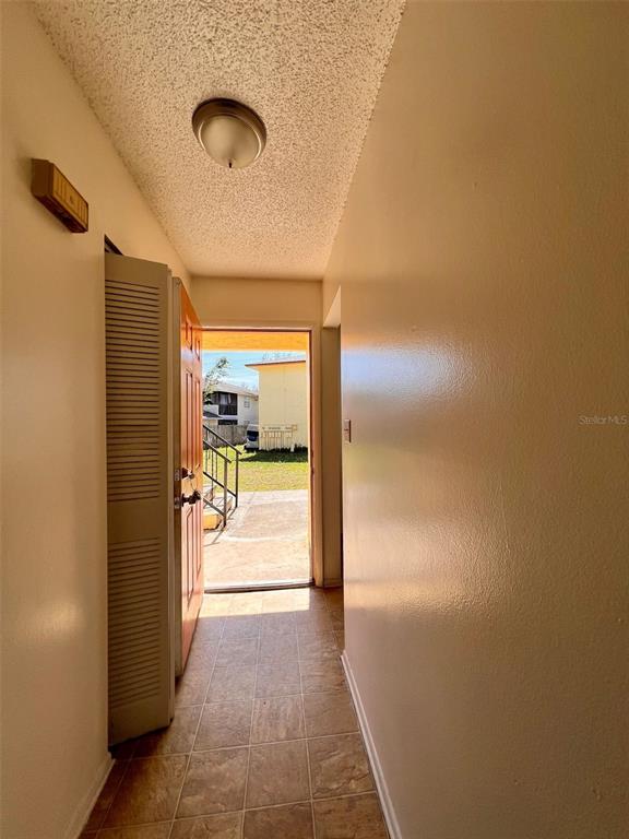 A tiled entryway leads to an open door revealing a view of an outdoor area — 2192 KNOX MCRAE DRIVE UNIT 1, TITUSVILLE, FL