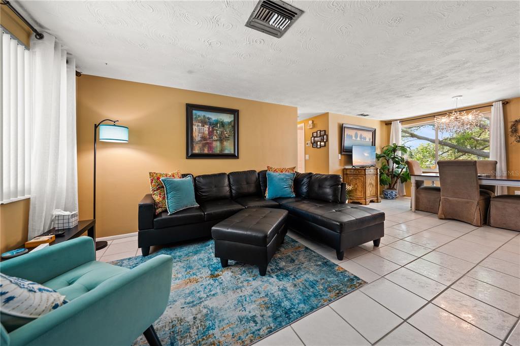 A living room with a black sectional sofa, blue rug, and tile flooring — 4114 SUNRAY DRIVE, HOLIDAY, FL