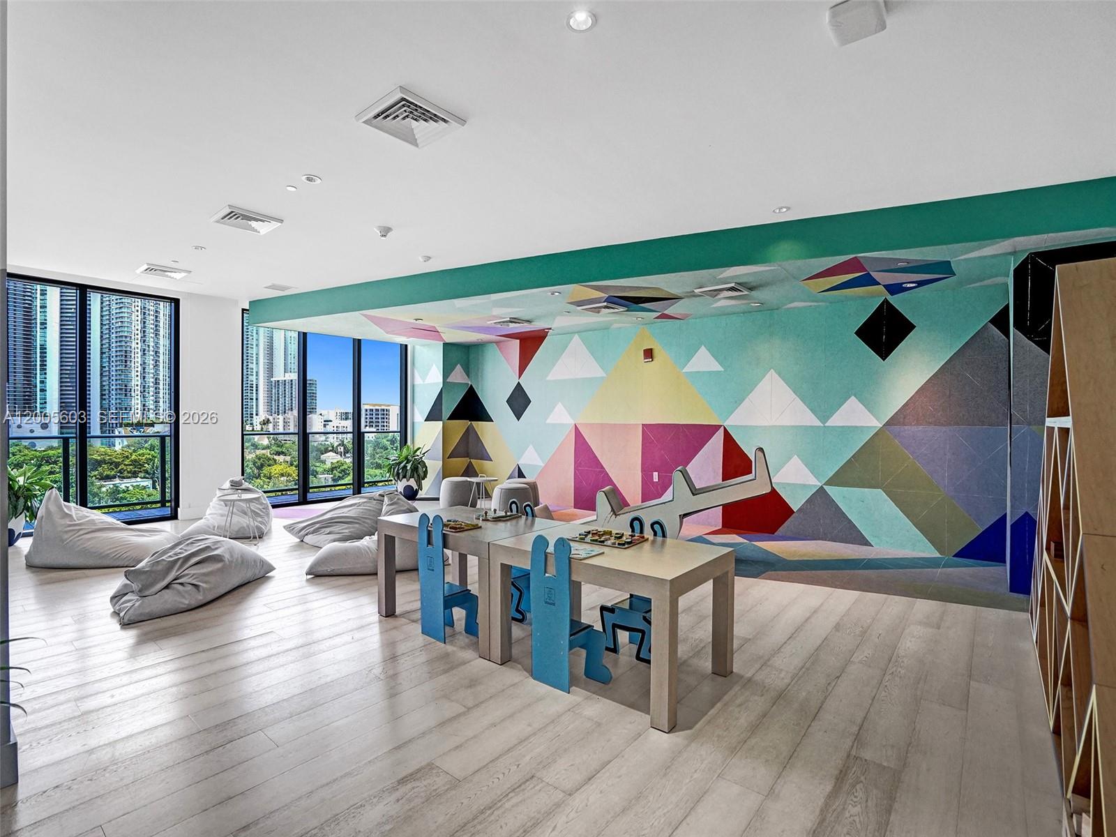 A children's playroom features a geometric mural, light wood flooring, beanbag chairs, and small tables — 121 NE 34th St # 1806A, Miami FL 33137, MIAMI, FL