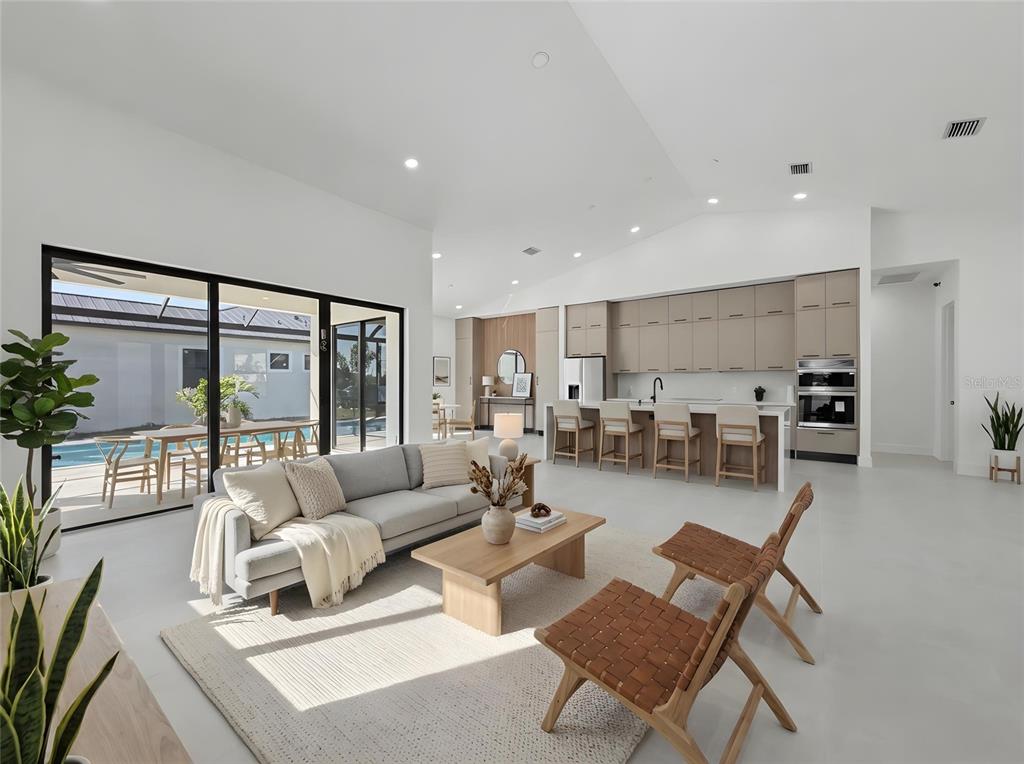A modern open-concept living room and kitchen feature light wood cabinetry and large sliding doors — 14687 LILLIAN CIRCLE, PORT CHARLOTTE, FL