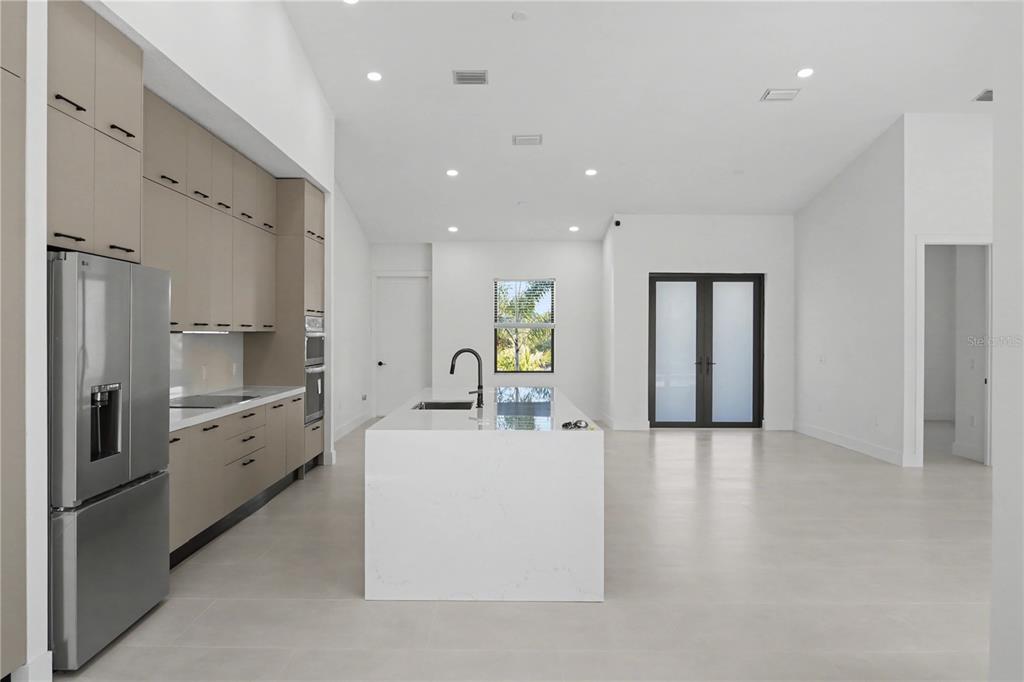 A modern kitchen features light-toned cabinetry, a white waterfall island, and light tile flooring — 14687 LILLIAN CIRCLE, PORT CHARLOTTE, FL