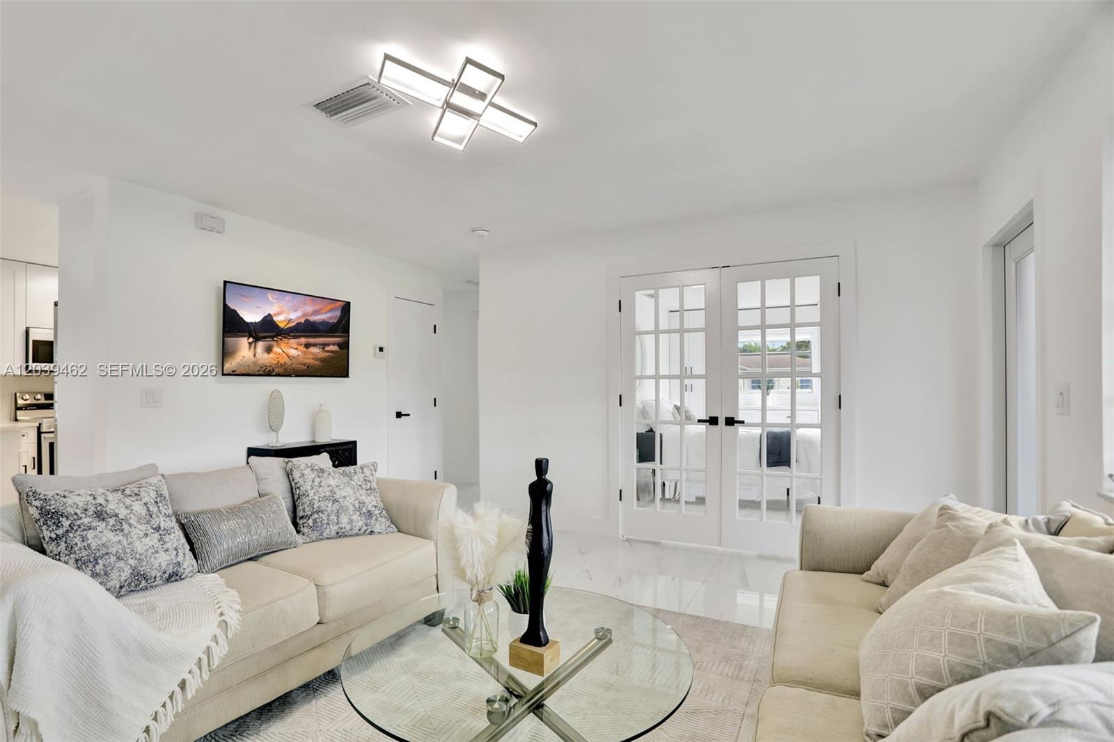 A bright living room features white walls, marble floors, a glass coffee table, and sofas — 1220 NE 8 St, Pompano Beach FL 33060, POMPANO BEACH, FL