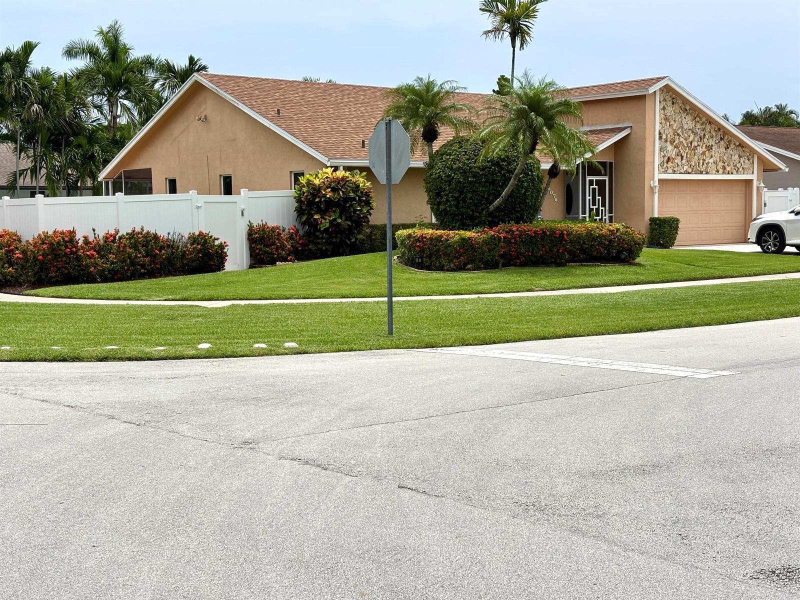 A single-story house with a tan exterior, stone facade, and a white fence — 1076 SW 26th Terrace, Deerfield Beach FL 33442, DEERFIELD BEACH, FL