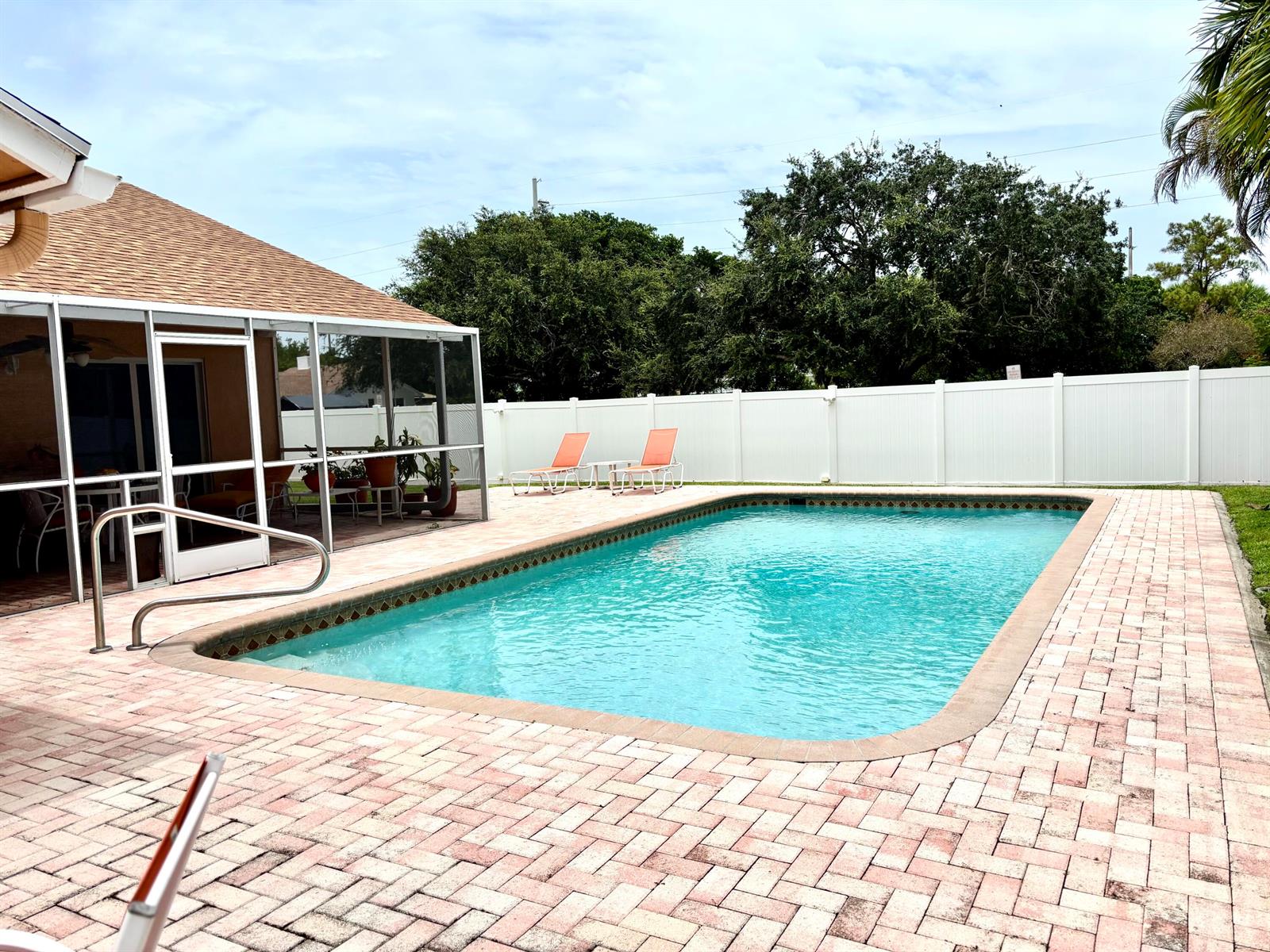 A rectangular swimming pool sits on a brick patio next to a screened-in porch — 1076 SW 26th Terrace, Deerfield Beach FL 33442, DEERFIELD BEACH, FL