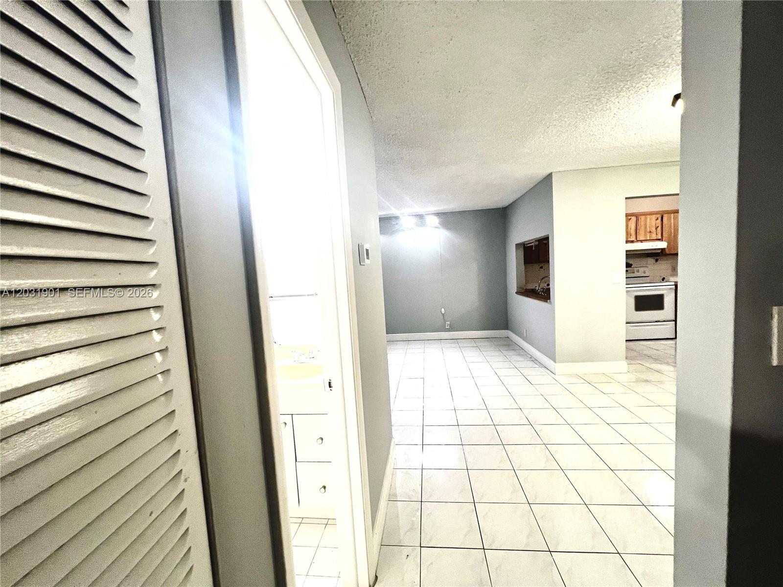 A tiled hallway leads to a living area with a kitchen pass-through window — 10002 Winding Lake Rd # 203, Sunrise FL 33351, SUNRISE, FL