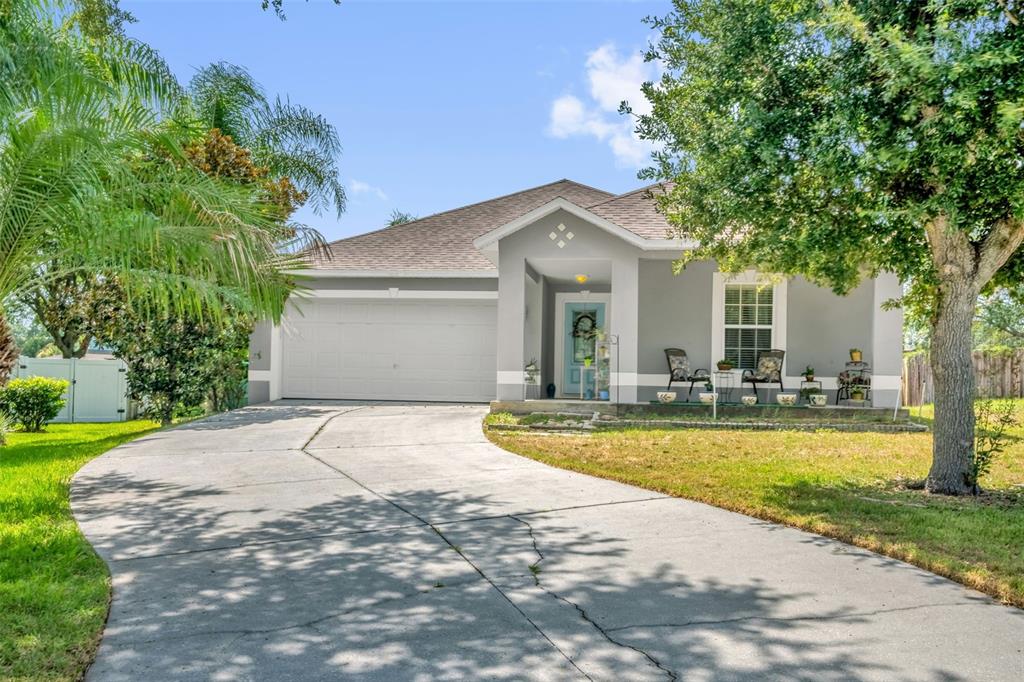 A gray single-story house with a two-car garage, a front porch, and a concrete driveway — 839 MARIETTA LANE, EUSTIS, FL