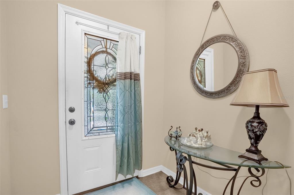 An entryway features a white front door with a glass insert, a mirror, and a console table — 839 MARIETTA LANE, EUSTIS, FL