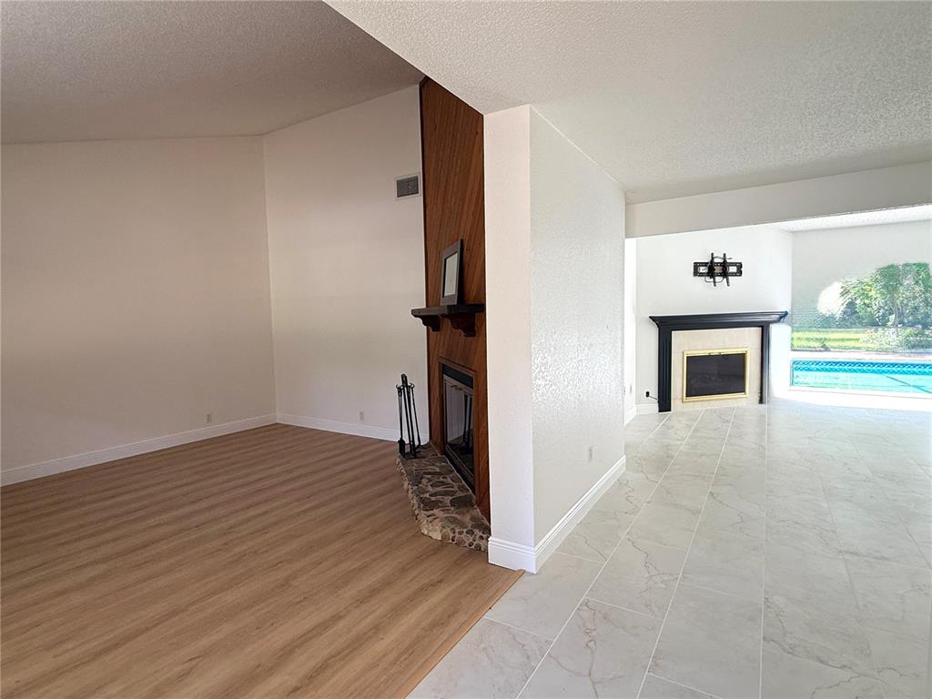 A living area with wood-look flooring and a fireplace connects to a tiled room beyond — 18306 CRAWLEY ROAD, ODESSA, FL