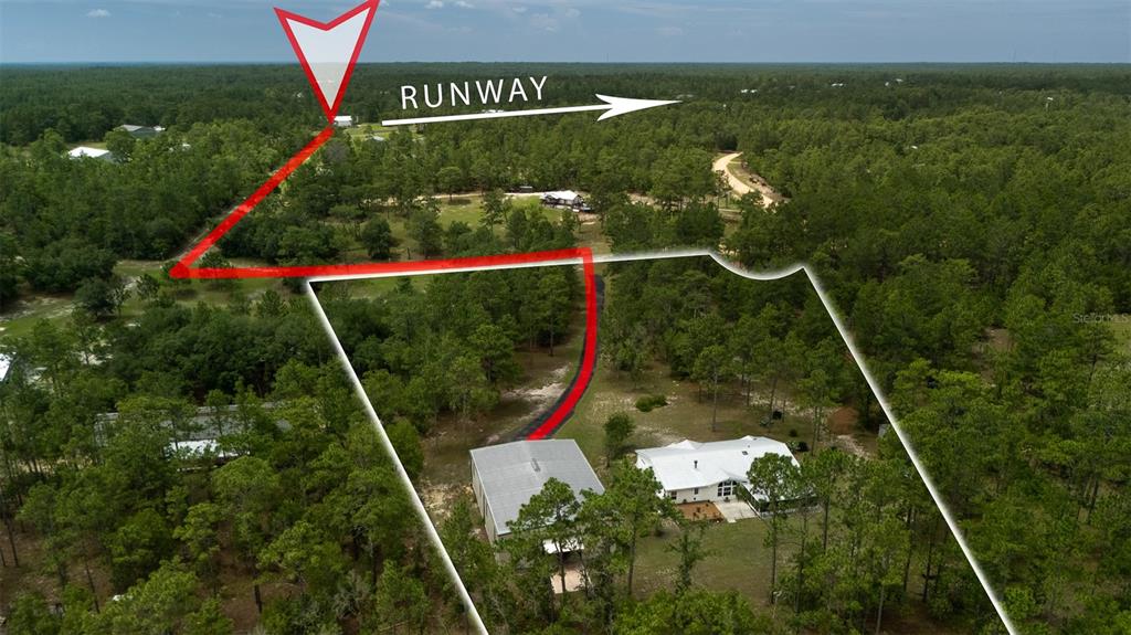An aerial view shows a house and detached garage with a driveway leading toward a runway — 267 MELROSE LANDING DRIVE, HAWTHORNE, FL