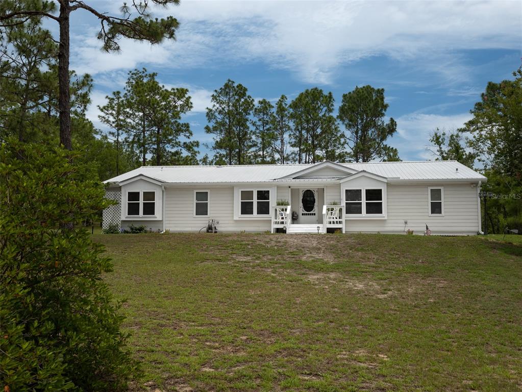 A single-story white house with a metal roof sits on a grassy lot — 267 MELROSE LANDING DRIVE, HAWTHORNE, FL
