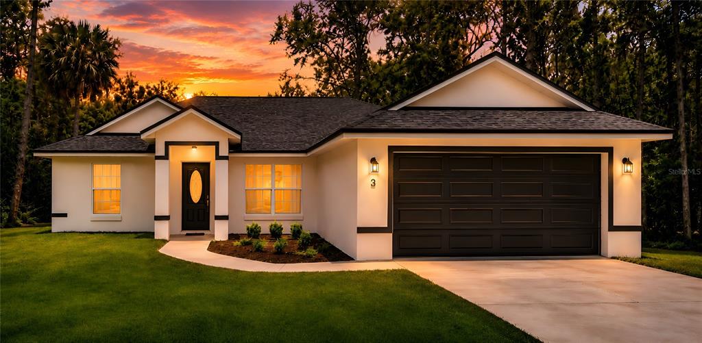 A single-story house with a white exterior, dark roof, and a two-car garage at sunset — 3 SEQUOIA DRIVE TRACE, OCKLAWAHA, FL