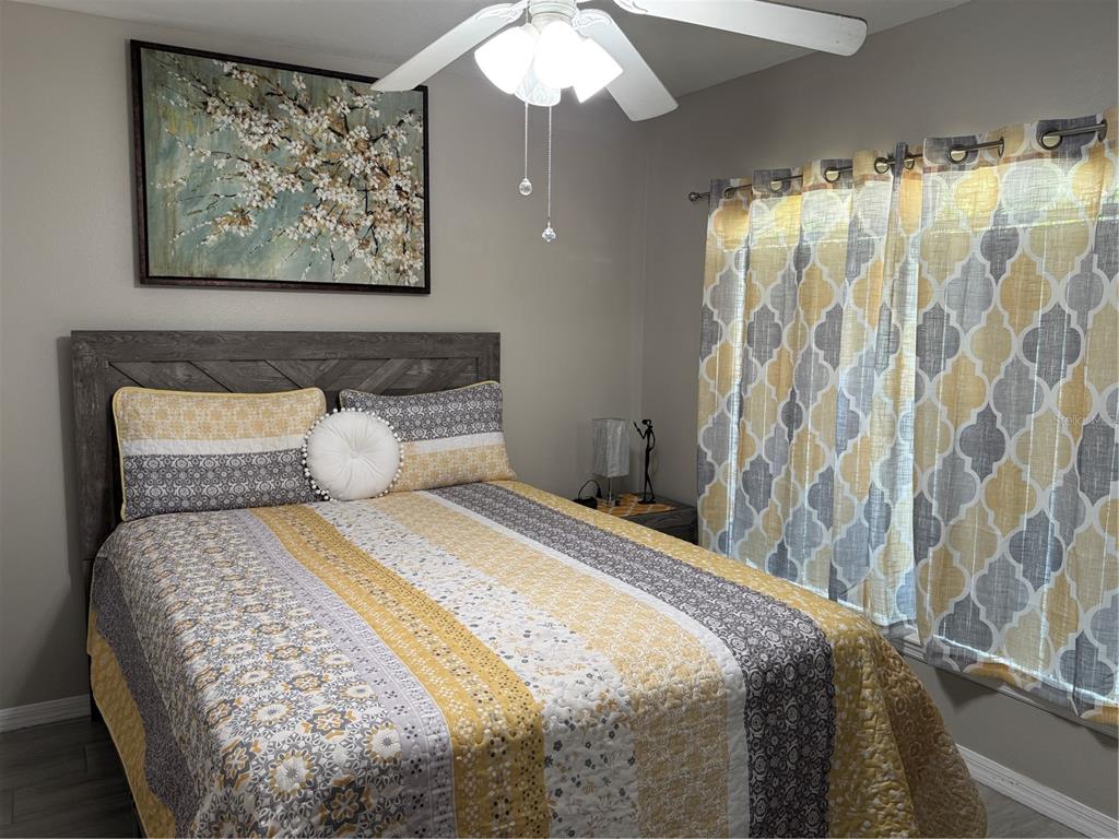 A bedroom features a bed with a yellow and gray patterned quilt and matching curtains — 1126 SANDY RIDGE DRIVE, DAVENPORT, FL